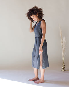 Model, Natalia, wearing the Charcoal romp around reversible dress. The side slit is showing and the dress is tied with a braided belt. Size M shown. 