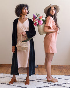 Model, Natalia, wearing Soluna Collective's romp around reversible dress. The fabric is a lightweight Tencel and is a light peach color. The Velvet Duster is paired with the dress in this photo. Size M shown. 